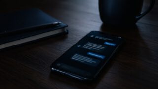 暗い机のスマホに表示された怪しいメッセージ・投資詐欺のイメージ