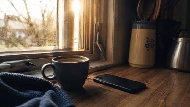 朝日の差し込む窓辺のコーヒーとスマートフォン