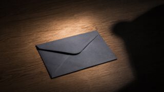 スポットライトの当たる封筒に静かに伸びる影